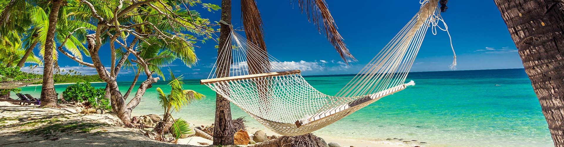 Hängematte am Strand, türkisblaues Meer und Palmen