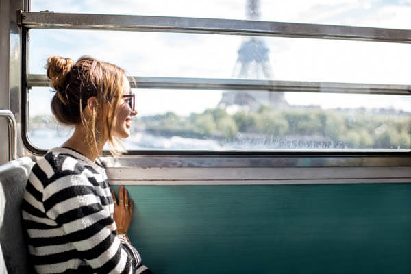 Frau mit Sonnenbrille fährt im Zug am Eiffelturm vorbei